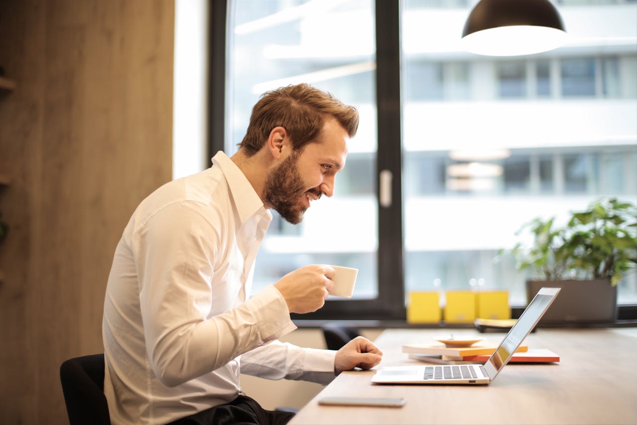 A person smiling at his desk after finding a merchant services portfolio buyer