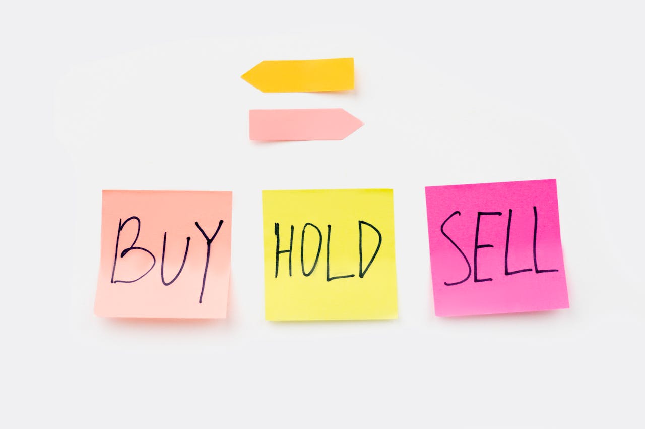 A set of sticky notes with the words buy, hold, and sell
