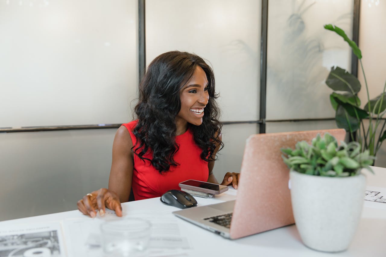 A smiling woman at a laptop, earning residual income from clients’ transactions