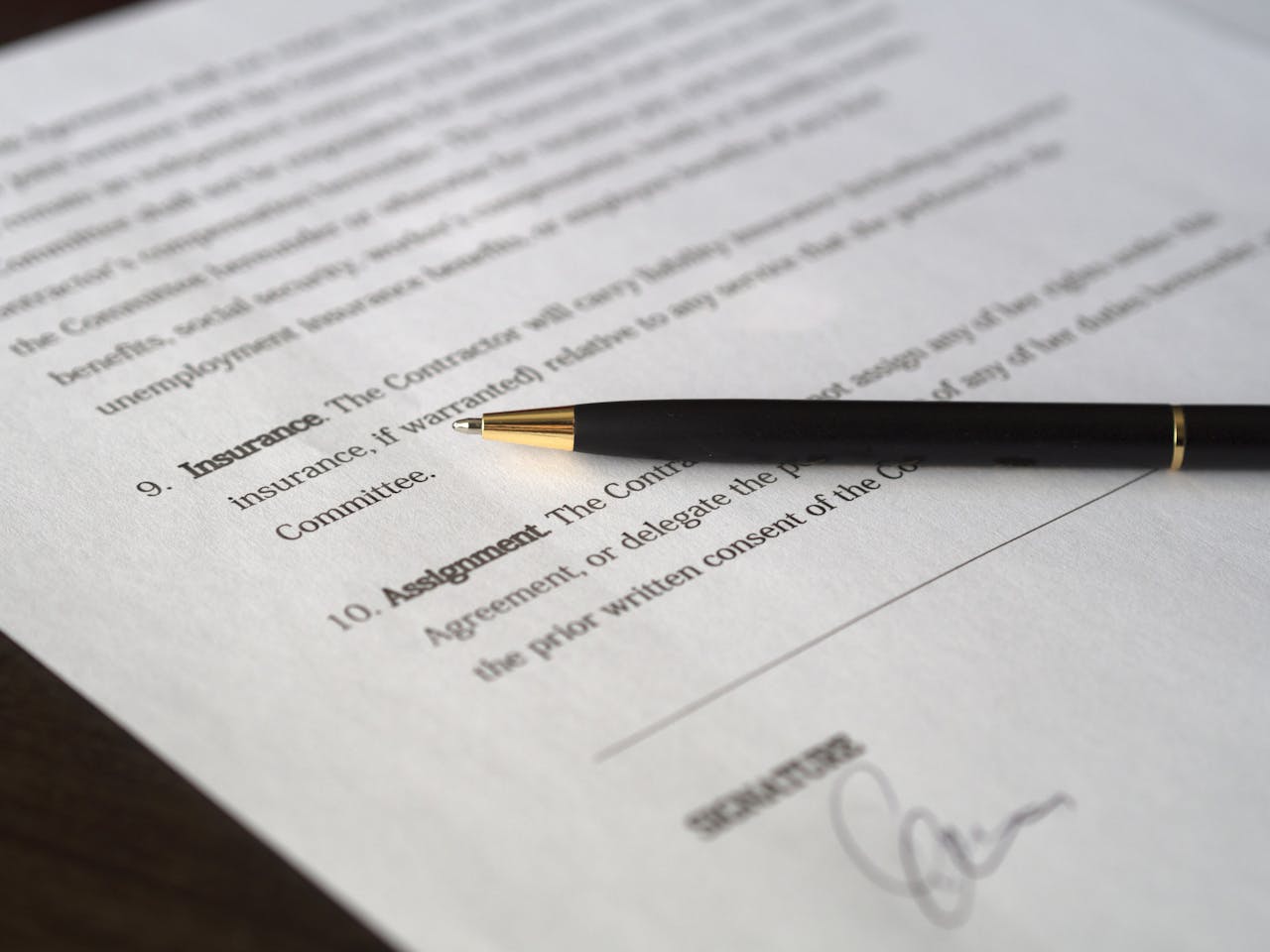 A pen next to a contract about to be signed after someone learns key terms before signing a merchant deal