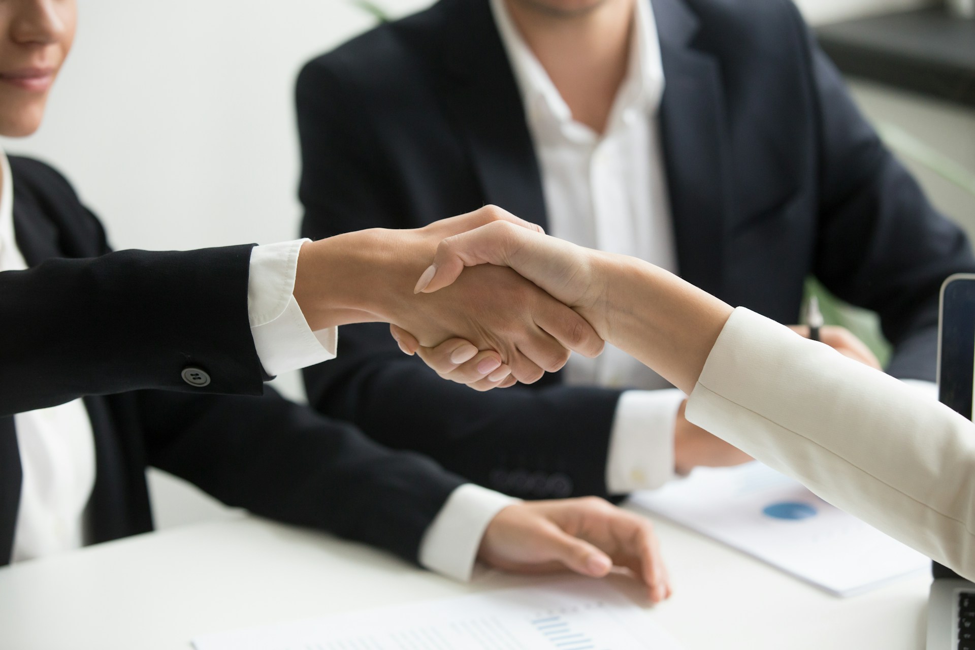 Two people reaching across a table to shake hands