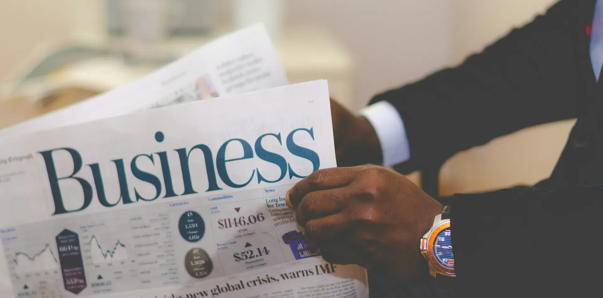 A person in a suit reading a business newspaper article about understanding merchant residual income