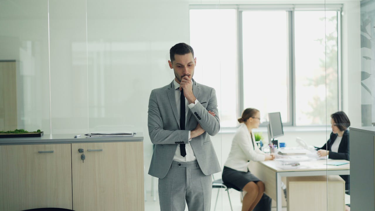 A man in a suit standing and looking contemplative