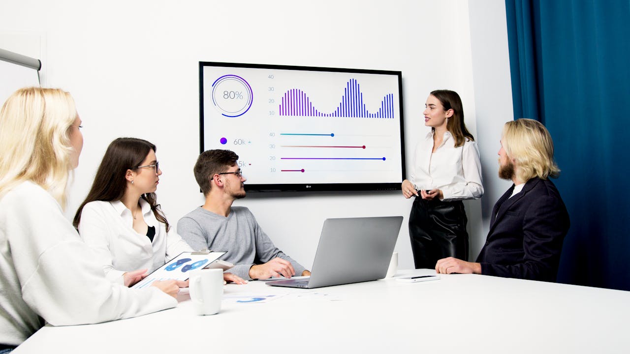 A group of people sitting at a table looking at a screen of analytical data