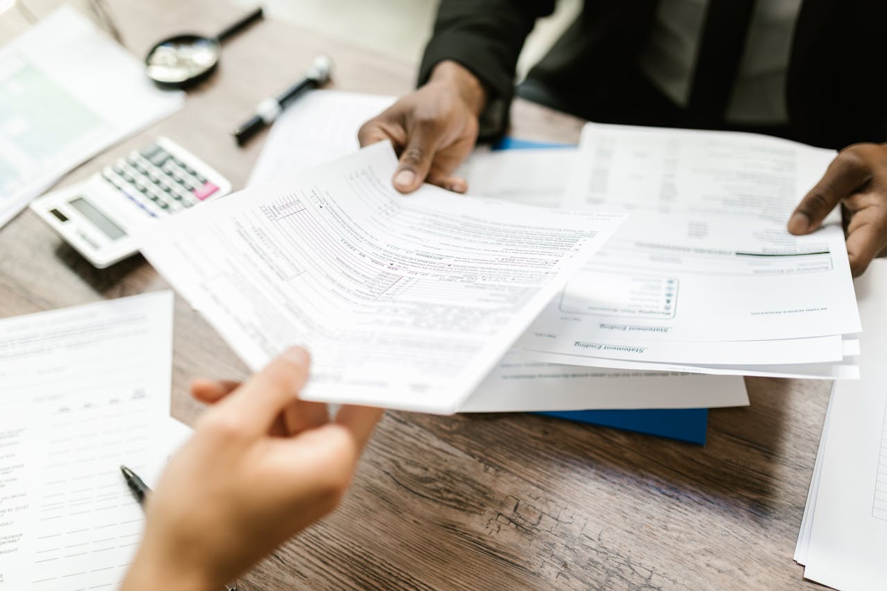 Two people handing off documents while discussing the best tactics to deepen existing merchant relationships