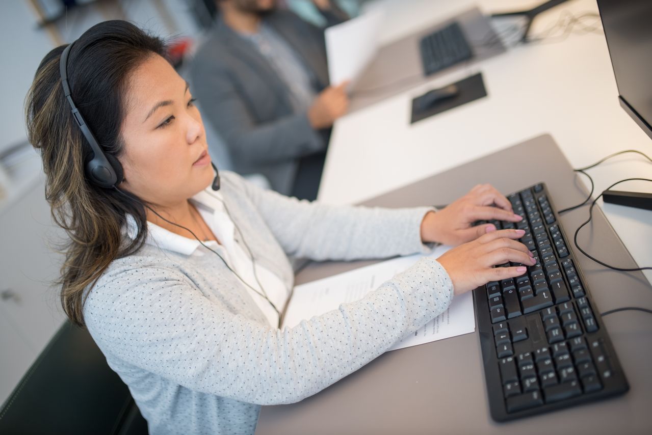 A woman typing on a keyboard while providing merchant services back office support