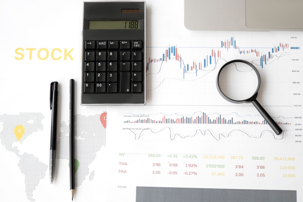 Financial documents next to a magnifying glass and calculator as someone is preparing for a merchant portfolio transfer